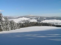 Zimní pohled od Suchého vrchu: Zprava Křížová hora (734m), Luzný s viditelnou sjezdovkou (718m), Kamenáč (729m) a Lískovec (775m). Upostřed v pozadí nejvyšší Jeřáb (1002m).