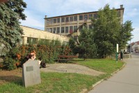 Památník Adolfa Esslera, v pozadí budova esslerovy továrny