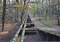 Kovové potrubí vedoucí okrajem rezervace