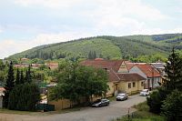 Ostrá hora se zvedá přímo nad obcí Česká, za ní dominuje hlavní hřeben Baby