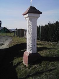 7. Boží muka v Pošné. Z mohutného soklu vyrůstá bíle olíčený oktogonální pilíř ukončený čtvercovou hlavicí s komolou jehlancovou stříškou a rytým letopočtem 1609.