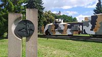 V popředí pomník železničářům, za ním vagón pro tank. V pozadí vížka zámku