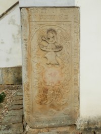 Pískovcový náhrobek vlevo od vchodu do kostela