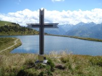 Pohled na jezírko od kříže na Bürener Höhe (1.929 m n.m.). Vzadu Vysoké Taury (Hohe Tauern)