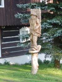 Dřevěná socha pašeráka u chalupy na začátku stezky