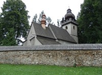 Kostel je za kamennou zdí se stříškou krytou šindely
