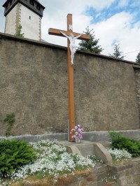 Dřevěný kříž s Ježíšem u hřbitovní zdi