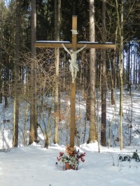 Dřevěný kříž s Ježíšem vpravo od kaple