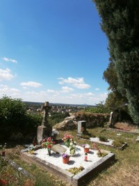 Na hřbitově se stále pochovává, v pozadí silueta Hazmburku
