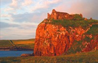 Západ slunce nad skotských hradeb vysoko na skále nad mořem
