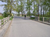 Pohled z Oseckého mostu na pravé předmostí a Osek: Další most za parkovištěm vede přes mlýnský náhon Strhanec, který v těchto místech ještě kopíruje v bezprostřední blízkosti tok Bečvy.