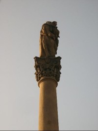 Vrchol sloupu: Na  vrcholu  sloupu  stojí  socha  sv.  Anny Samotřetí s Ježíškem a Pannou Marií v náručí. 