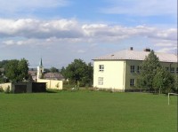 Slavkov: Pohled na obci, vlevo kostel, vpravo škola, v popředí sportovní hřiště