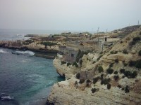 Bejrút. Zátoka Středozemního moře, severozápaní pohled, v pozadí dobře patrné rybářské domky. Za výběžkem se nacházejí Holubí skály. 