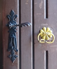 detail dveří se zdobenou klikou a klepadlem
