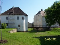zachovalé hradby navazující na bílou budovu (Muzeum u Vodní branky v Uničově) z boku