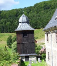 Zvonice: Těsně pod kostelíkem stojí na kamenné podezdívce dřevěná zvonice.