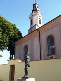 soška a veža neďalekého kostola