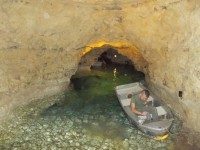 zamestnenec jaskyne vyberá vodu z jednej z lodiek