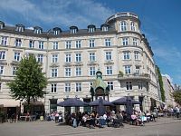 budova s ,,parížským,, nádychom, veža s hodinami, ľudia posedávajú na terasách reštaurácii