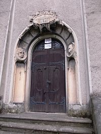 vchod do veže kostola, po bokoch dva portréty