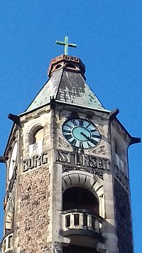 okno s balkóbikom, nápis, hodiny a koruna s krížom