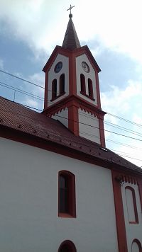 štvorhranná veža s hodinami a zvukovými oknami ukončená trojuholníkovými štítmi a ihlancovou strechou
