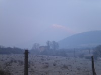Milešovka osvícená vycházejícím sluníčkem jak vychází z raní mlhy od obce Chotiměř (24.2.2011).
