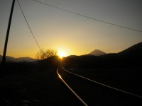 Zapadající sluníčko za Liščí vrch a Milešovka od železničního přejezdu v Dobkovičkách.