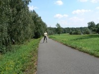 Dívka na bruslích na stezce po hrázi řeky Ostravice. Vpravo plocha na jiné využití volného času 