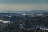 Výhled z vrcholu Špičáku (841 m n. m.) k v lesích ukrytému kostelu sv. Mikuláše (nalevo od něj část autokrosového areálu) v Dobřanech, na vodní nádrž Rozkoš a zcela v dáli dokonce vrchol podkrkonošské Zvičiny