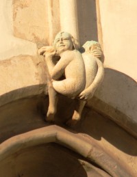 Neslušný mužíček nad oknem věže v létě