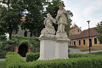 Sousoší sv. Jana Nepomuckého s postavou klečící prosebnice se nachází za kostelem