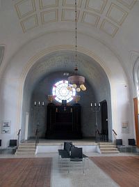 Bima (vyvýšené místo v synagoze) na východní straně synagogy s aron ha-kodeš (svatá schránka, v niž jsou ukryty svitky Tóry). Prostoru dominuje velké pseudorozetové okno s vitráží Davidovy hvězdy.