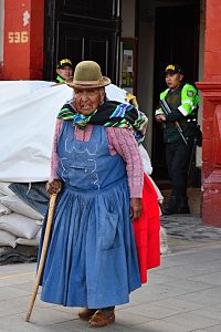 Peru - stařenka ve městě Puno, vzadu zátarasy u policejní stanice