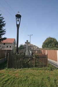 skromný křížek se zvoničkou leží přímo u silnice