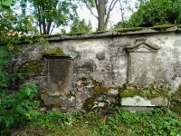 hřbitovní zeď s vytesanou kamennou hlavou.