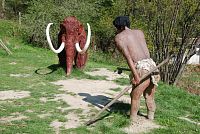 Pračlověk čeká na mamuta aby si ho mohl upéct na uhlí