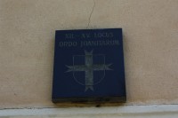 Řádový znak johanitů umístěný nad vchodem do kostela v Orlovicích