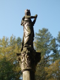 Hlavice a socha na vrchu sloupu