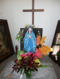 Improvizovaný oltářík s Pannou Mariií, křížem a obrazy po straně