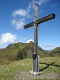 Dřevěný kříž na vrcholu. Špička za křížem je Rossgruberkogel (2.156 m n.m.)