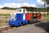 Motorová lokomotiva ČKD BN30 U z roku 1959 s výletním vozem vlastní stavby Muzea průmyslových železnic z roku 2002 před branou do muzea ve Zbýšově