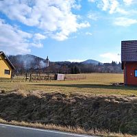 Cečstou od hřbitova pohled na kostel a v dáli vykukující horu Milešovku