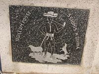 symboly pečate obce z polovice 19. storočia - postava stojacého pastiera s palicou, klobúkom a fajkou, okolo neho je ovca a skákajúci pes