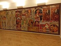 stena s plagátmi Alfonsa Muchy