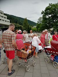 muž s kočiarom mieriaci na piknik, skupinka ladiaca do červena