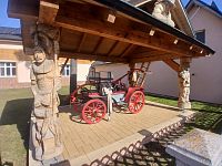 hasičská ručná striekačka pod krásne zdobeným dreveným prístreškom