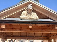 zo štítu prístrešku nad hasičskou striekačkou sa na okoloidúcich prizerá hasič