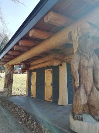 drevenú stavbu podopiera medveď, dvere vedúce na WC